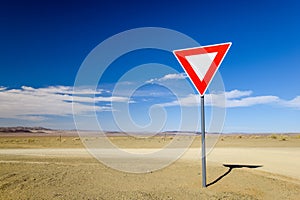 Wide angle view of a give way yield sign at a gravel road intersection in the Namibian Desert between Ai-Ais Fish River Canyon a