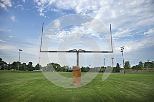 Wide angle view of a goalpost on a football field with beautiful clouds