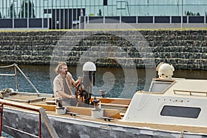 Wide angle view at handsome young man sailing boat on river