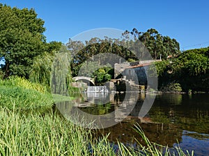 Wide angle view over Este River in Portugal, reeds in foreground with stone ruins and old Roman bridge photo