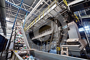 Wide angle view at recycling plant conveyor belt transports garbage inside drum filter or rotating cylindrical sieve with trommel