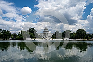 Wide angle view of the United States Capitol Building in Washington DC on a partly cloudy summer day, on the reflecting pool