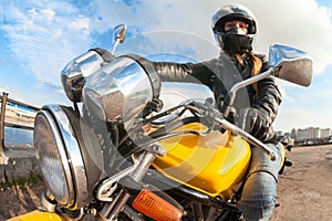 Wide angle view at young woman motorbiker sitting on bike, focus on headlight