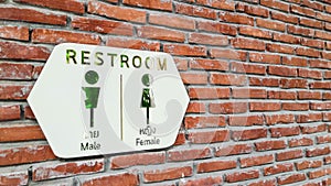 Wide angle of white restroom sign on bricked wall.