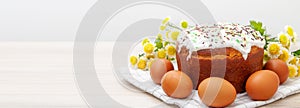 Wide banner with Easter cake and colored eggs yellow flower blossoms on background. Holiday food and easter concept. Copyspase for