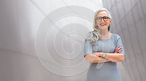 Wide banner panorama portrait of elder, senior, older CEO business woman standing confident, smiling, with arms folded, copy space