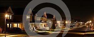 wide banner of residential neighborhood at night with lights and copy space area for real estate and home ownership concepts
