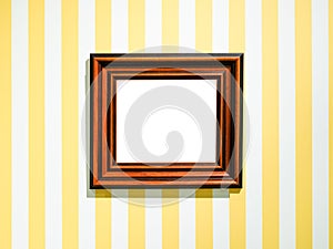 Wide brown picture frame on striped yellow wall