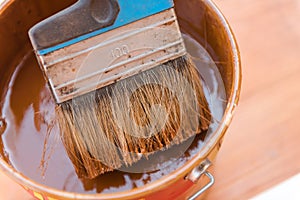 A wide brush in the paint. Brush the terrace. The brush lies on a can of paint. Blue brush in the paint