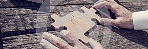 Wide close up on unidentifiable business person with hands putting together two puzzle pieces