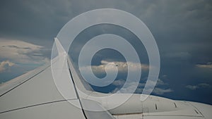 Wide footage of Aircraft flying in dark clouds airplane Wing as seen by passenger through porthole windows.