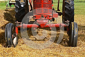 Wide front wheeled red tractor pulling a baler