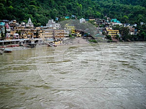 Wide ganga river having village on the other side. Brown colour ganga river in Rishikesh India
