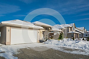 Wide garage of luxury house with driveway and front yard in snow