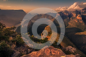 Wide high-angle view of the Three Rondavels and Blyde River Canyon in delicate warm tones at Sunset Golden Hour.