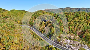 Wide highway road in North Carolina leading through Appalachian mountains with yellow fall forest and fast moving