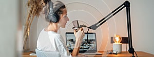 Wide image. Woman podcaster streaming and broadcasting her podcast from homemade studio