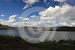 a wide lake on a grassy mountain side under a blue sky