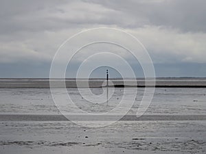 The wide landscape view of watt, sand and water of the northern sea in norddeich mole germany