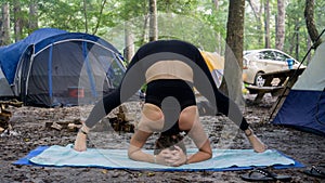 Wide-Legged Forward Bend prasarita padottanasana yoga pose Young woman doing yoga while camping in the forest