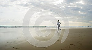 Wide lens silhouette of afro American runner woman jogging on the beach - young attractive and athletic black girl training