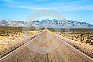 Wide open road and distant mountains in wide open Nevada desert along the Extraterrestrial Highway