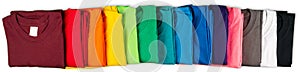 Wide panorama banner row of many fresh new fabric cotton t-shirts in colorful rainbow colors isolated. Pile of various colored