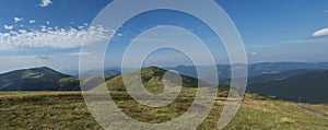 Wide panorama of grassy green hills and slopes at ridge of Low Tatras mountains with hiking trail footpath, mountain