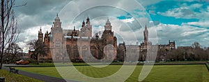Wide panorama of Kelvingrove art gallery in Glasgow on a cloudy spring day. Beautiful green grass in front of it