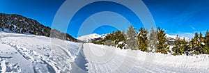 Wide panorama with road leading to snow covered mountains and forest, Andorra, Pyrenees