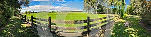 WIde panorama of wooden fence and grassland.