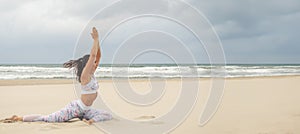 Wide panoramic shot of Young beautiful slender woman doing yoga on the sand beach