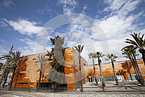 Wide panoramic view, orange building and palm trees. Blue sky with clouds