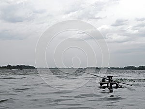 The wide river on a gray cloudy day. Cozy bridge for fishing. Silver waves on dark water