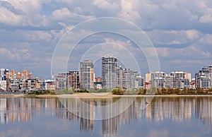 wide river with reflection of blue sky with clouds and city on the horizon