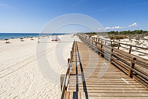 Wide sandy beach with wooden bridges along dunes in Monte Gordo, Algarve, Portugal