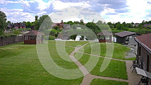 Wide shot beautiful landscape on eco-resort with wooden biuldings green meadow and lake. Scenics in tourist resort