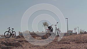 Wide shot bicycles in sunshine on Cyprus resort. No people on rocky beach on sunny summer day.