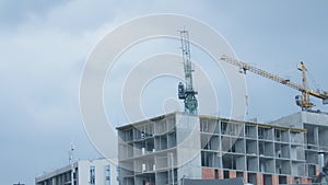 Wide shot building under construction with large tower crane turning outdoors. Heavy industrial equipment working on