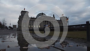 Wide Shot of Bundestag, Reichstag in Berlin, Germany with German Flag waving in wind on cloudy day