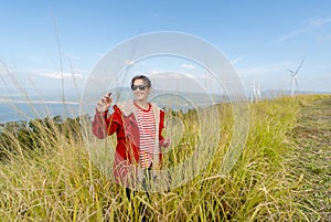 Wide shot of Caucasian woman with red coat and sunglasses stand in the meadow with happiness and smiling also look to left side