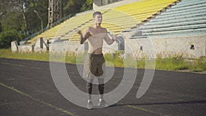 Wide shot of cheerful sportsman using jumping rope for training outdoors. Portrait of happy young Caucasian man working