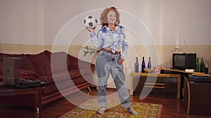 Wide shot confident retro woman posing with soccer ball indoors at home in 1980s 1990s. Wide shot positive redhead