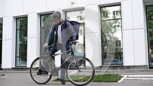 Wide shot of courier male riding bike to customer house, putting bicycle on footboard and leaving for delivery on foot.