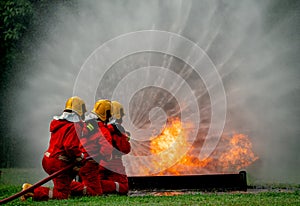 Wide shot of firefighter team with three man support together to distinguish fire using water curtain to control area of fire