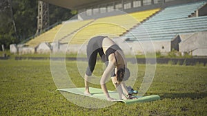 Wide shot of flexible young woman standing in yoga pose on exercise mat. Portrait of beautiful slim Caucasian yogi