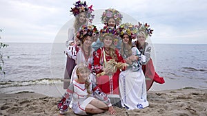 Wide shot gorgeous Ukrainian women and girl posing in slow motion on sandy river beach outdoors. Group of confident