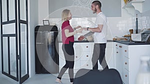 Wide shot of happy loving couple dancing in kitchen at home. Young Caucasian man and woman having fun on weekends