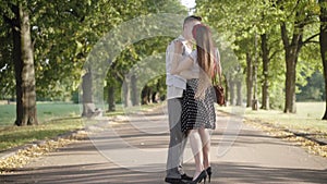 Wide shot of happy young couple strolling and start dancing in sunlight in summer park. Portrait of loving joyful