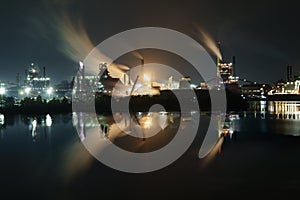 Wide shot of an industrial part of a city near the deep blue ocean at night